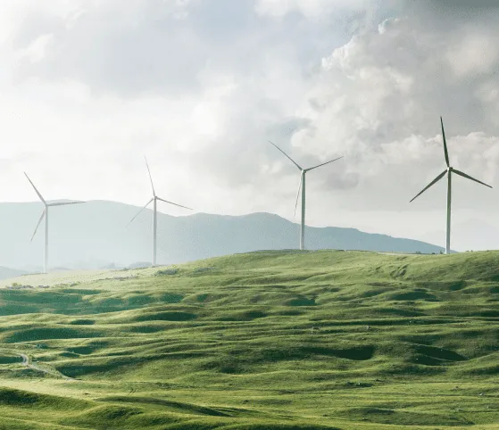 Rolling green hills with wind turbines in the background, symbolizing Toshiba's commitment to sustainable power generation and clean energy solutions.