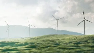Wind-powered energy-generated windmills on a green hillside.