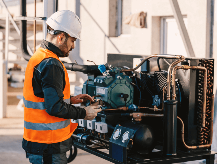 Technician in hard hat and safety vest working on industrial equipment, representing Toshiba's on-site services for manufacturing and critical infrastructure.