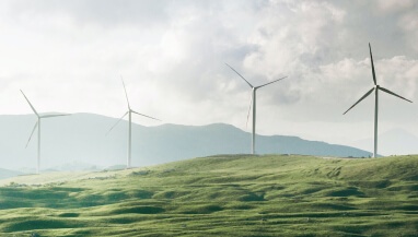 Wind-powered energy-generated windmills on a green hillside.
